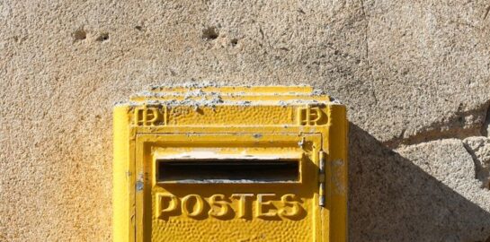 yellow steel mail box mounted on gray wall